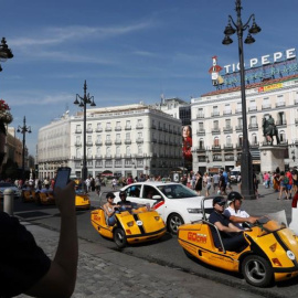 Un hombre toma fotos de turistas en una visita autoguiada de Gocar en la Plaza Puerta del Sol de Madrid. REUTERS/Susana Vera