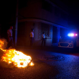 Policías dominicanos apagan una barricada encendida en protesta por el extenso apagón, debido a que el 85% del país se encuentra sin energía eléctrica tras el paso de la tormenta tropical Erika hoy, viernes 28 de agosto de 2015, en la zona 