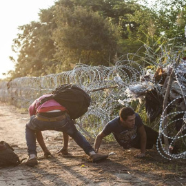 Varios refugiado pasan la alambrada en la frontera entre Hungría y Serbia cerca de Roszke (Hungría). / SANDOR UJVARI (EFE)