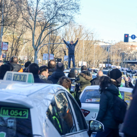 Un taxista se sube a un coche para dar una charla durante una concentración de taxistas en el Paseo de la Castellana de Madrid, donde el colectivo acampó en su séptimo día de huelga. | Ricardo Rubio / Europa Press