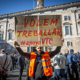 Un conductor de VTC porta un cartel con la consigna "Volem Treballar #apoyoVTC" en la Plaza de Sant Jaume - David Zorrakino/ EP