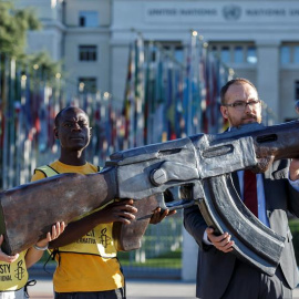 Activistas de Amnistía Internacional sujetan una réplica de un fusil AK-47 con el cañón torcido durante una protesta contra el Tratado sobre Comercio de Armas (ATT) en la segunda conferencia de estados miembros de este tratado (CSP2), delan