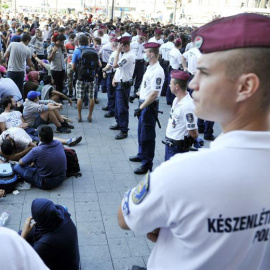 Polícias húngaros observan a los inmigrantes que permanecen ante la estación de ferrocarriles Keleti de Budapest. / EFE