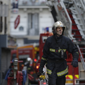Un bombero trabaja en las labores de extinción del incendio declarado en un bloque de viviendas en París. /AFP