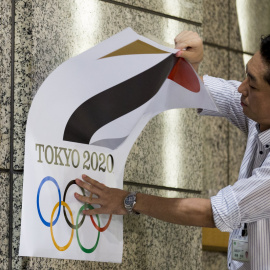 Un empleado retira un cartel con el logotipo de Tokio 2020, que tendrá que ser sustituido. /REUTERS