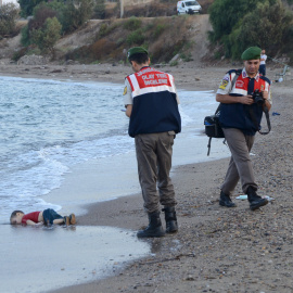 Dos agentes de la gendarmería turca, junto al cadaver de un niño que formaba parte del grupo de refugiados sirios que naufragaron intentando llegar a la isla de Kos. REUTERS/Nilufer Demir