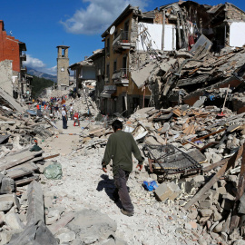 Un hombre camina entre los restos de los edificos derruidos por el terremoto en Pescara del Tronto, Italia.  REUTERS/Remo Casilli