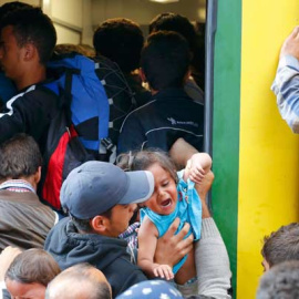 Variso refugiados sirios intentan subirse a un tren en la estación de Budapest. / LAZSLO BALOGH (REUTERS)