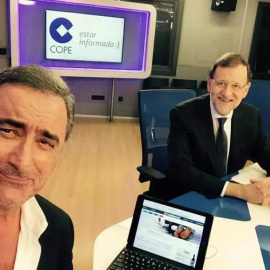 El presidente del Gobierno, Mariano Rajoy junto al periodista Carlos Herrera durante su entrevista en la cadena Cope. Foto del Twitter de Herrera. En la pantalla del ordenador se puede ver la foto del niño ahogado en la playa de Turquía.