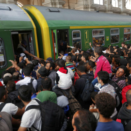 Decenas de refugiados intentan subirse a un vagón de tren entre empujones. /REUTERS