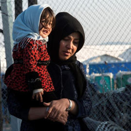 Una mujer carga a su bebé mientras se dirige al centro de registro de migrantes tras cruzar la frontera entre Macedonia y Grecua, en Macedonia. EFE