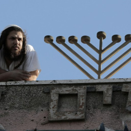Un colono judío en la azotea de una antigua casa de una familia palestina en Jerusalén Este. - AFP