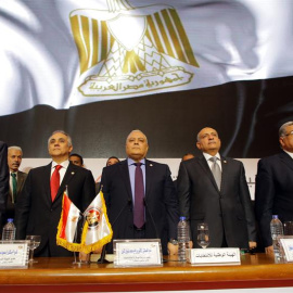 El jefe de la Comisión Nacional Electoral egipcio (NEC), Lasheen Ibrahim (c), y otros miembros no identificados, permanecen de pie antes de ofrecer una rueda de prensa en la que anuncian los resultados finales de las elecciones presidencial