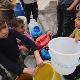 Unos niños esperan que para recoger agua potable en la ciudad siria de Alepo. REUTERS/Giath Taha