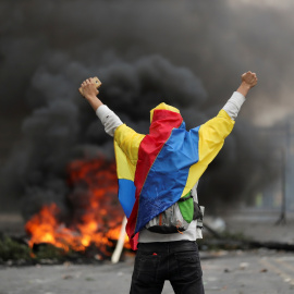 Un manifestante cubierto con una bandera ecuatoriana se para frente a una barricada durante una protesta contra las medidas de austeridad del presidente de Ecuador, Lenin Moreno, en Quito, Ecuador, 8 de octubre de 2019. REUTERS / Ivan Alvar