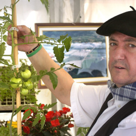 Un "baserritarra" (agricultor) muestra una mata de tomate en la inauguración de una feria de agricultura en Bilbao. / EFE