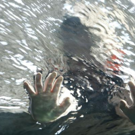 Un niño mete sus manos en el agua./EFE