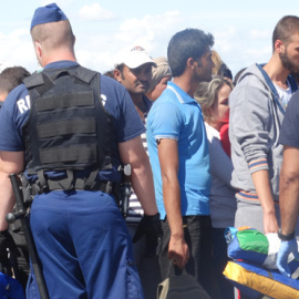 La policía rodea a los refugiados que acaban de cruzar la frontera. / CORINA TULBURE