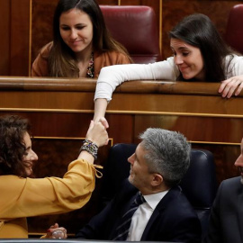 La ministra de Hacienda, María Jesús Montero (i - 1ªfila), estrecha la mano con la portavoz de Podemos en el Congreso, Irene Montero (d - 2ª fila), durante su intervención en la segunda jornada del debate de las enmiendas a la totalidad del