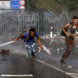 Un grupo de inmigrantes protesta en la frontera mientras la Policía húngara les rocía con gases y cañones de agua. REUTERS