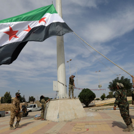 14/10/2019 - Los combatientes rebeldes sirios respaldados por Turquía alzan la bandera de la oposición siria en la ciudad fronteriza de Tel Abyad. REUTERS / Khalil Ashawi