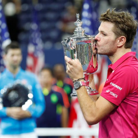El suizo Stanis Wawrinka besa la copa de campeón del US Open con Djokovic de fondo. /EFE