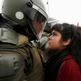Un manifestante mira a un policía antidisturbios durante una protesta marcado golpe de 1973 el ejército del país en Santiago , Chile. REUTERS/Carlos Vera