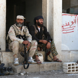 Dos milicianos rebeldes descansan junto a sus armas en la gobernación de Quneitra. - REUTERS