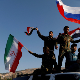 Sirios ondean las banderas de Irán, Rusia y Siria en protesta por los ataques en Damasco. /REUTERS