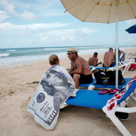 Un turista usa una toalla con el diseño de un billete de 100 dólares en la playa de Santa María en las afueras de La Habana (Cuba). REUTERS / Alexandre Meneghini