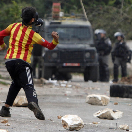 Un niño palestino tira una piedra a policías israelíes durante una protesta. REUTERS/Abed Omar Qusini