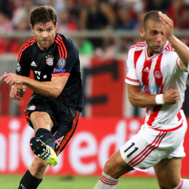 Xabi Alonso lanza un balón junto al el jugador Pajtim Kasami, durante partido entre Olympiacos y el Bayern Múnich de la Liga de Campeones. EFE/ALEXANDROS VLACHOS