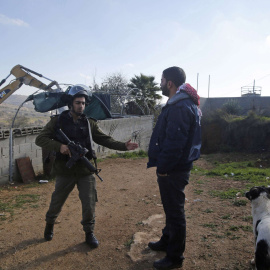 Un policía israelí habla con un palestino durante la destrucción de una empalizada en Hebrón. REUTERS/Mussa Qawasma