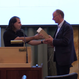 Nima Arkani-Hamed entrega una botella de coñac a su colega Poul Damgaard para saldar su apuesta, en Copenhague.- ACADEMIA DANESA DE CIENCIAS Y LETRAS