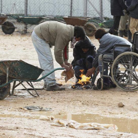 Refugiados sirios se calientan con una pequeña hoguera en el campo de refugiados Zaatari, cerca de Mafraq, Jordania. /EFE