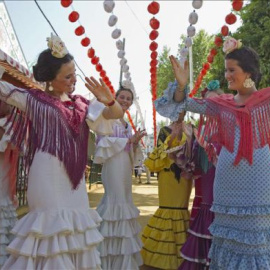 Jóvenes vestidas con el traje típico de flamenca bailan sevillanas en el Real de la Feria de Abril de la capital hispalense. EFE/Archivo