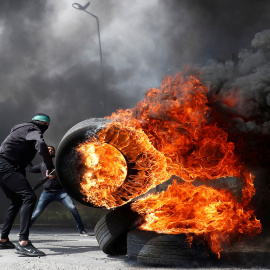 Un manifestante palestino mueve un neumático en llamas durante los enfrentamientos con las tropas israelíes. Reuters