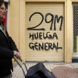 Dos personas pasan frente a un local cerrado durante la huelga general del 29 de marzo de 2012. Archivo.