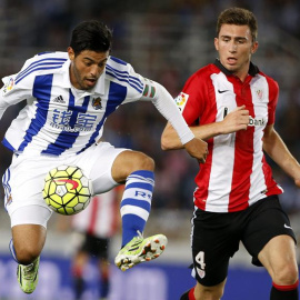 El jugador mexicano de la Real Sociedad Carlos Vela (i) juega un balón ante Laporte, del Athletic. /EFE