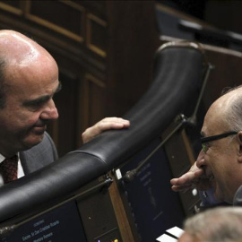 El ministro de Economía, Luis de Guindos, conversa con el ministro de Hacienda, Cristóbal Montoro, en el Congreso de los Diputados. EFE