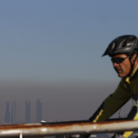 Un ciclista pasea por Pozuelo ante la boina de contaminación de Madrid. EFE
