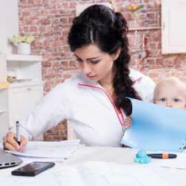 Una madre trabaja a la vez que sostiene a su hijo - FOTOLIA