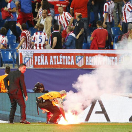 Un operario retira una de las bengalas lanzadas por hinchas del Benfica en el partido de anoche. /EFE