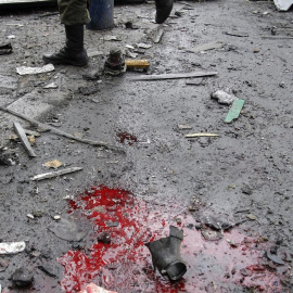 Un militar pasa ante un charco de sangre en la zona donde impactaron varios proyectiles de artillería en Donetsk (Ucrania), hoy, miércoles 11 de febrero de 2015. Al menos seis civiles murieron y otros ocho resultaron heridos por fuego de ar