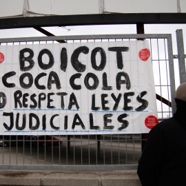 Un empleado de Coca-Cola junto a una pancarta que pide que la empresa acate la sentencia judicial. -JAIRO VARGAS