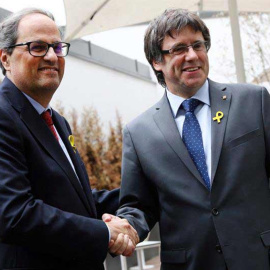 El recién elegido presidente de la Generalitat de Catalunya, Quim Torra (izq), estrecha la mano a su predecesor, el expresidente regional catalán Carles Puigdemont, en Berlín. (OMER MESSINGER | EFE)