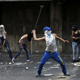 Varios palestinos lanzan piedras durante los enfrentamientos registrados con policías israelíes en la ciudad cisjordana de Hebrón.