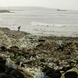 Un hombre recoge basura de entre los montones de plástico de una playa en el sur del Líbano, en la costa Mediterránea. AFP