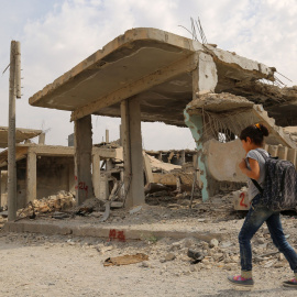 Los niños sirios caminan al lado de los escombros en su camino al colegio en el segundo día del nuevo año escolar, el 6 de octubre de 2015, en la ciudad kurda de Siria de Kobane. AFP PHOTO / delil Souleiman