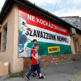 Dos niños inmigrantes pasan ante un cartel en Budapest que pide el 'No' en la consulta sobre migración. / REUTERS